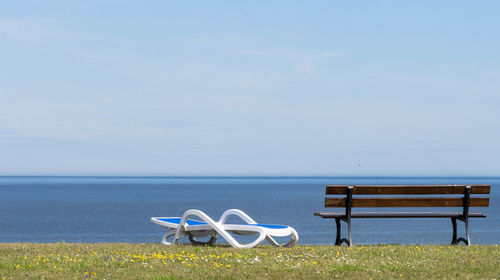 Deck chairs on beach against sky