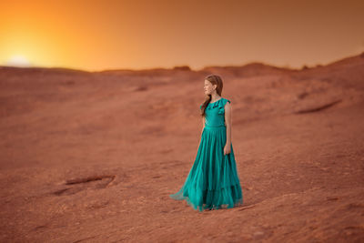 Rear view of woman standing on sand at desert