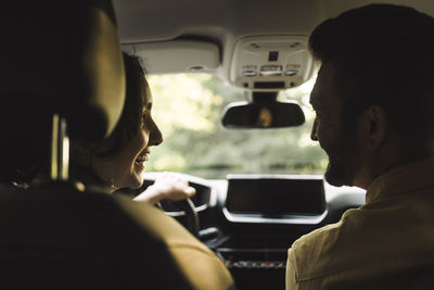 Happy woman looking at man sitting in car