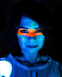 Close-up portrait of woman with face paint against black background