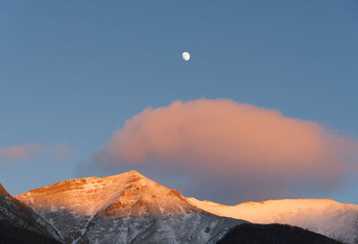 Scenic view of snowcapped mountains against sky at sunset with moon