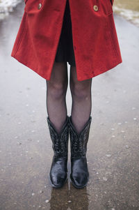 Low section of woman standing on puddle during rainy season