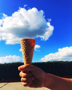 Cropped image of hand holding sea against clear sky