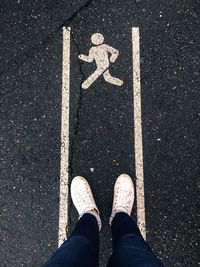 Low section of man standing by symbol on road