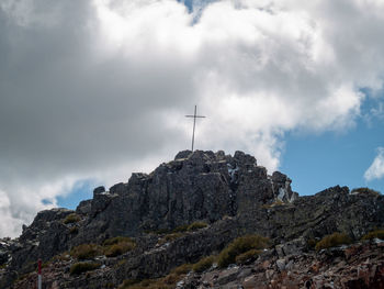 Low angle view of cross on rock against sky