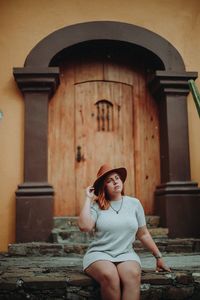 Full length of woman sitting against building