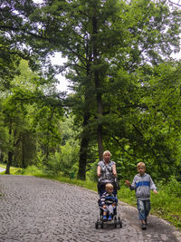 Family with boy walking on footpath against trees