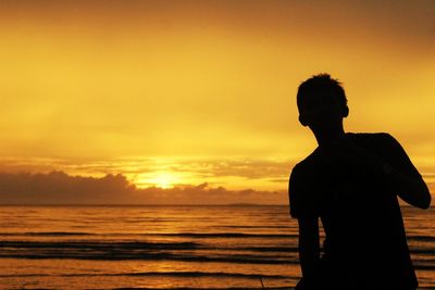 Silhouette man looking at sea against sky during sunset