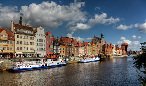 Boats in river against buildings in city