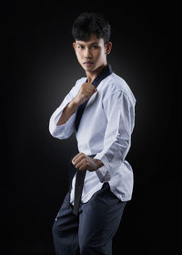 Young man standing against black background