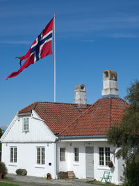 Flag by house against blue sky