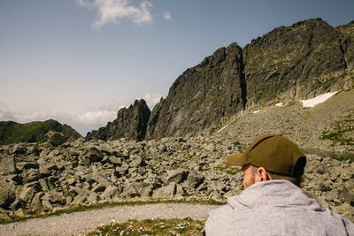 Rear view of man on rock against sky