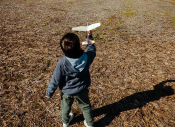 High angle view of boy playing with airplane model on land
