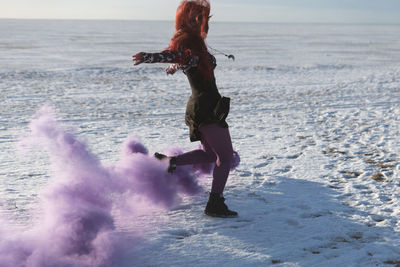 Full length of woman walking by distress flare at beach