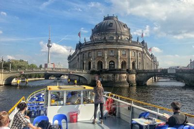 People in tourboat amidst spree river by bode-museum