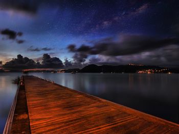 Pier over sea against sky at night