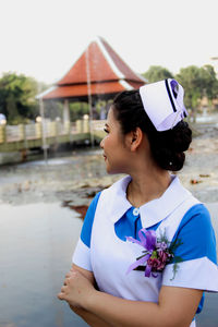 Young woman looking away while standing against built structure