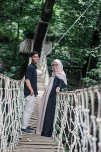 Portrait of friends standing on footbridge