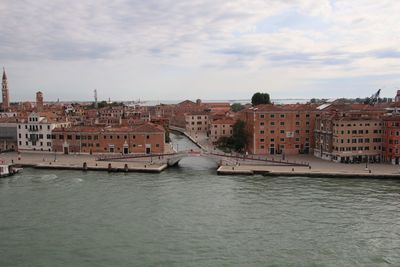 Buildings by river against sky in city