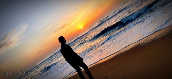 Silhouette man against sea during sunset