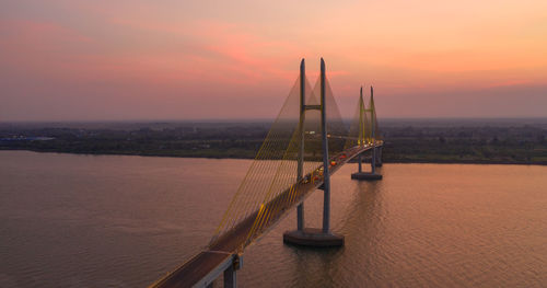 Bridge over river against romantic sky at sunrise