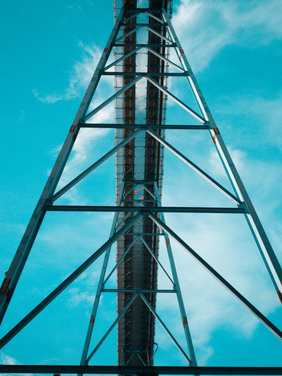 sky, low angle view, blue, built structure, architecture, cloud - sky, metal, day, nature, no people, tower, tall - high, outdoors, ladder, industry, connection, construction industry, directly below, grid, pattern, steel, power supply, alloy, turquoise colored