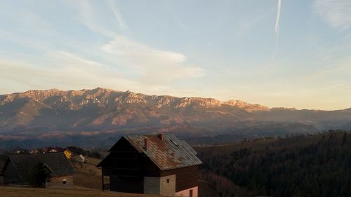 House amidst buildings against sky during sunset