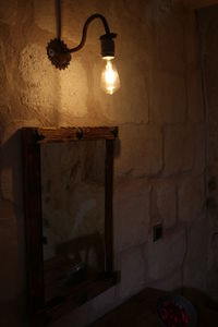 Illuminated lamp hanging on wall at home