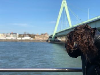 Woman standing by river against sky