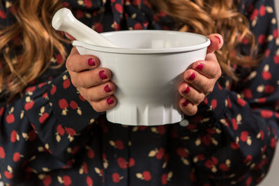 Midsection of woman holding white mortar and pestle