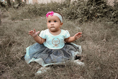 Portrait of cute baby girl sitting on land