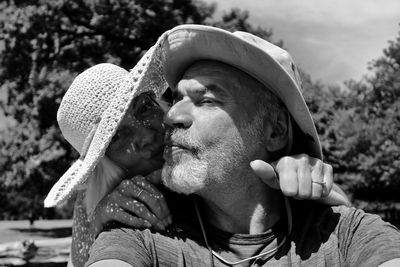 Couple wearing hat embracing while standing outdoors