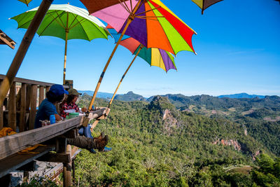 People sitting on mountain against sky