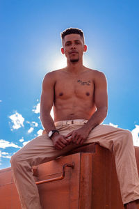 Portrait of young man sitting against sky