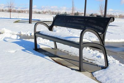 Empty chairs on beach against sky during winter