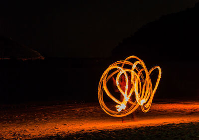 Light trails on beach against sky at night