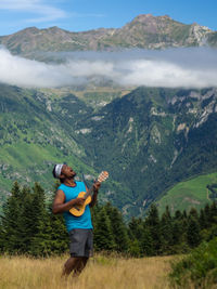 Man playing guitar while standing on mountain