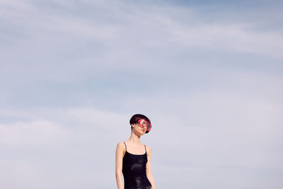 Portrait of young woman standing against sky