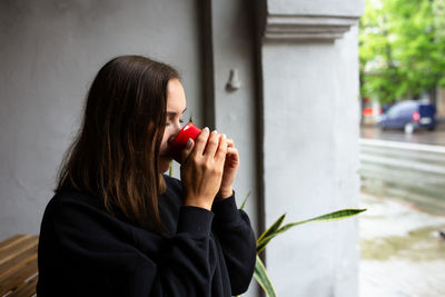 Young woman alone drinking a drink in a terrace cafe on a rainy day