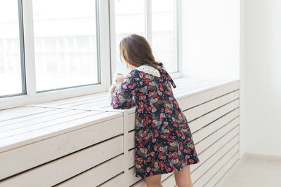 Rear view of woman standing by window