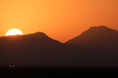 Scenic view of silhouette mountains against orange sky