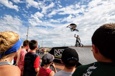 Rear view of people on motorcycle against sky