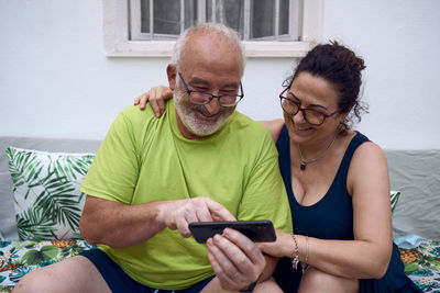 An elderly couple laughing while using a mobile phone. concept older couple