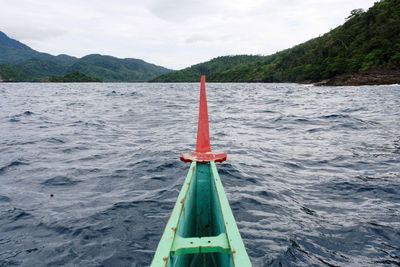 View from bow of indonesian traditional boat sailing in sea with mountains and sky background