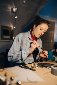 Female technician working on equipment at desk in workshop