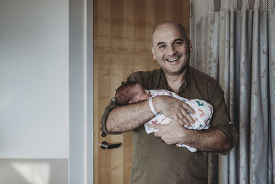 Father holding newborn boy wrapped in blankets in hospital