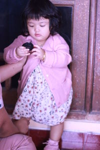 Full length of a girl holding mobile phone while sitting outdoors