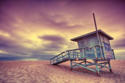 Hut on beach against sky during sunset