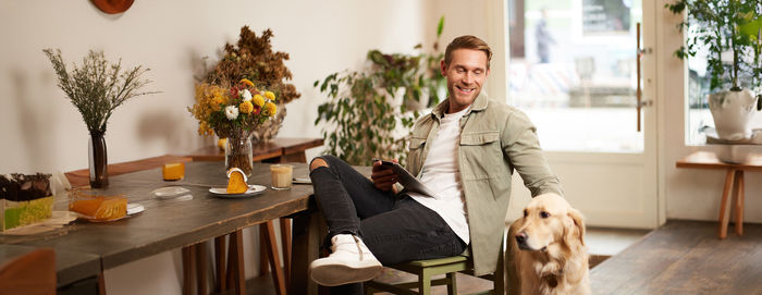 Portrait of young man using mobile phone while sitting on table