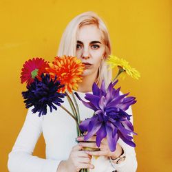 Close-up portrait of beautiful young woman against yellow background